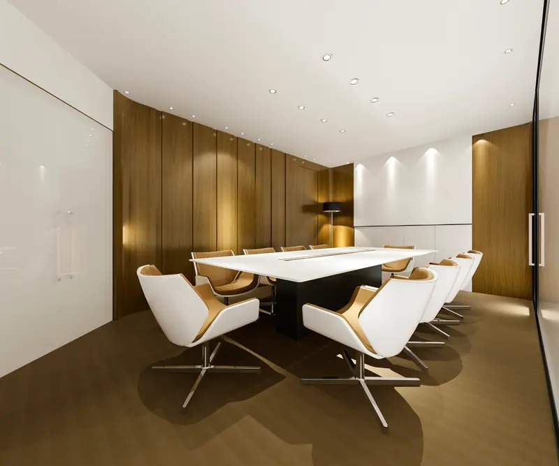 Salle de réunion aux boiseries claires, fauteuils blancs autour d’une table de conseil.