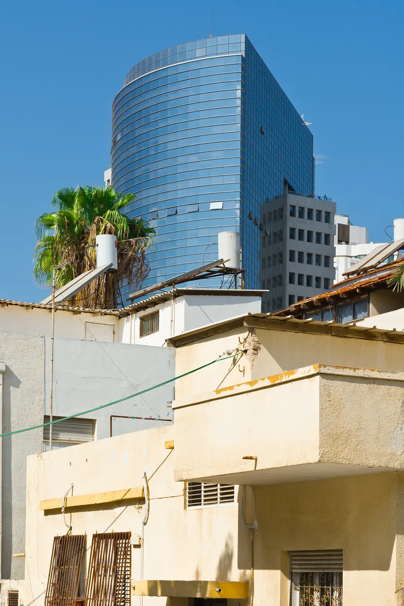 Toits d’une ville africaine au pied d’une tour de bureaux vitrée.